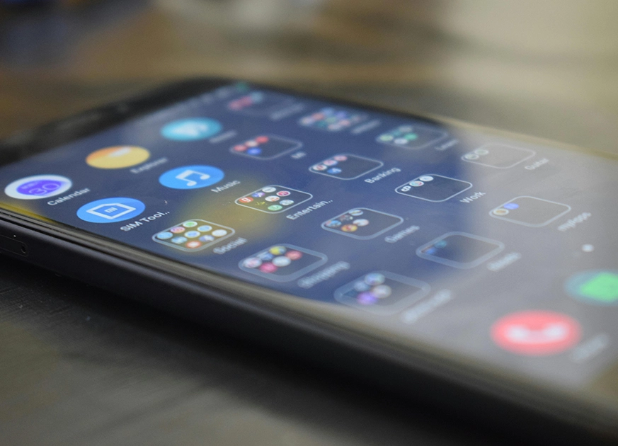 A smartphone screen shows a grid of app icons, including folders labeled "Social," "Games," and "Work," reflecting the variety app developers create.